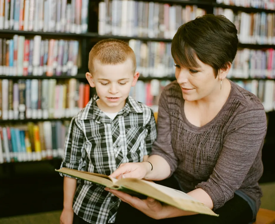 An adult reading with a child in a library